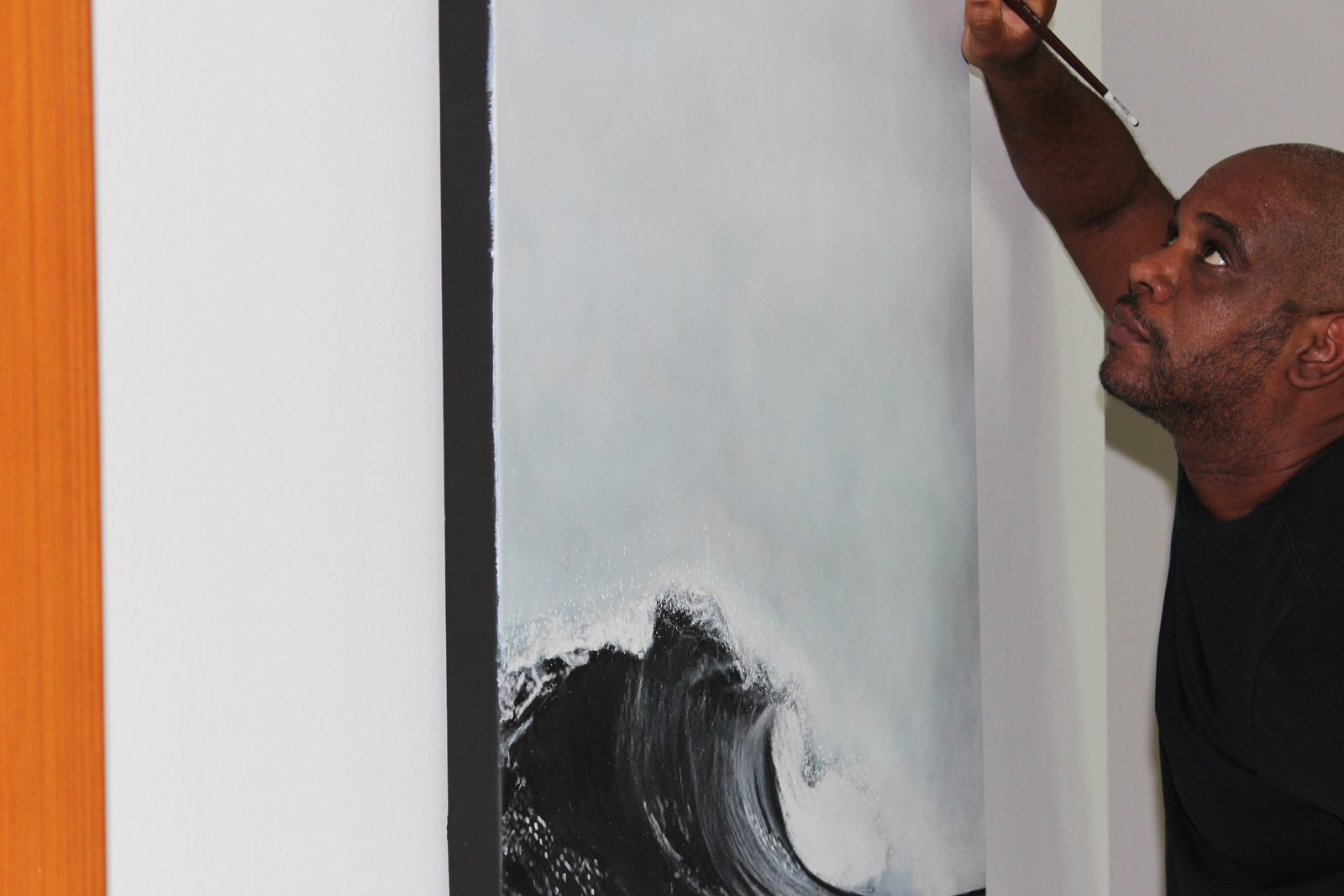 Raúl painting a wave on a large canvas