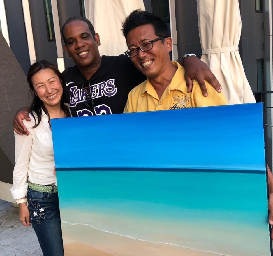 Raúl with two people holding a turquoise seascape